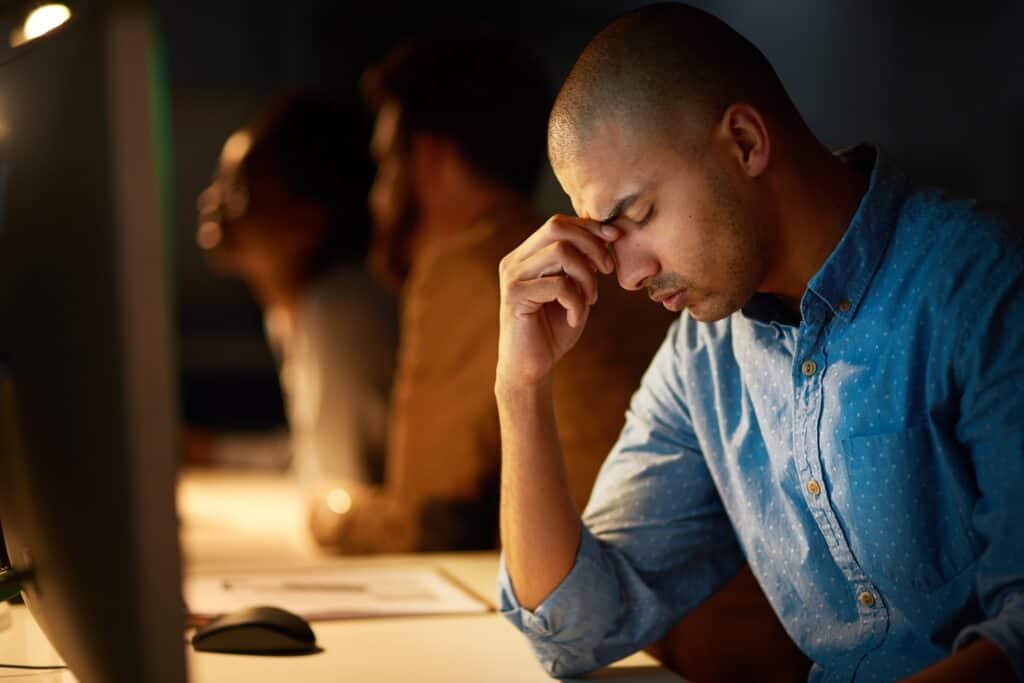 Cropped shot of a young businessman looking stressed out while working late in an office